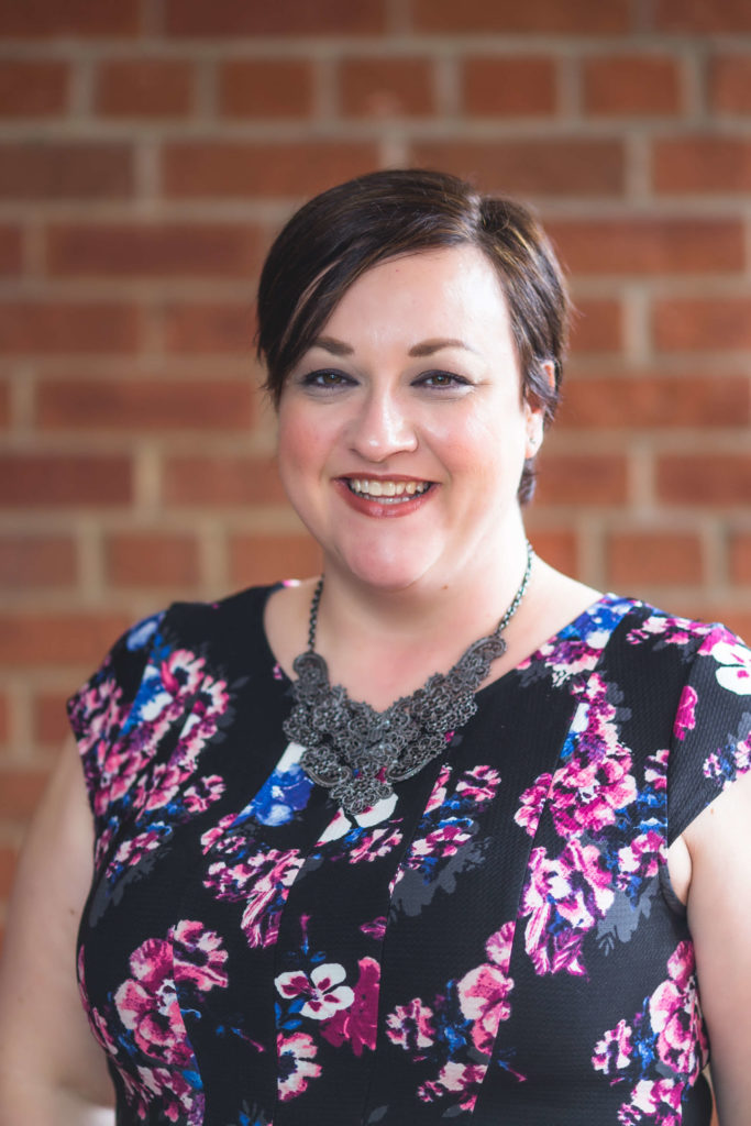 woman with short red hair and floral dress smiling