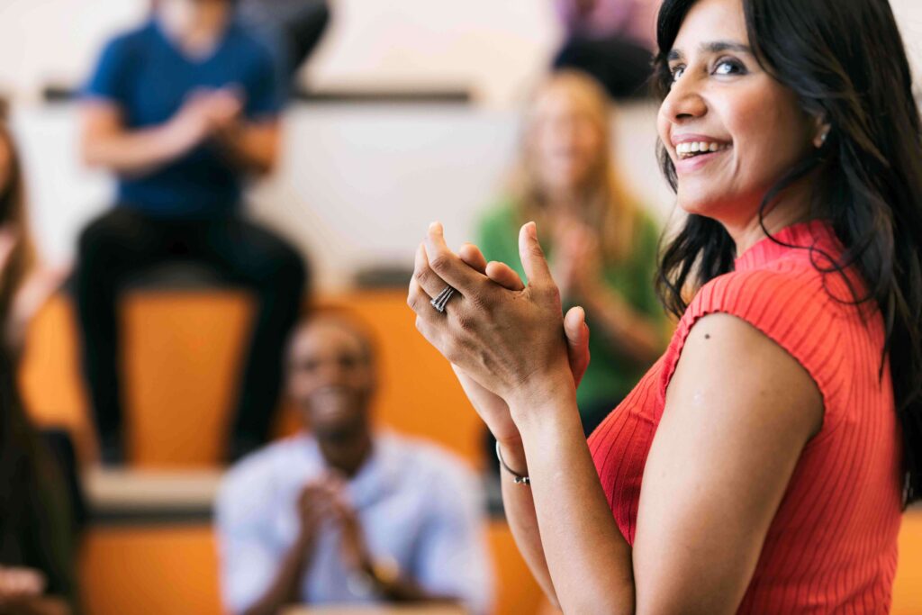 woman in coral shirt smiling and clapping