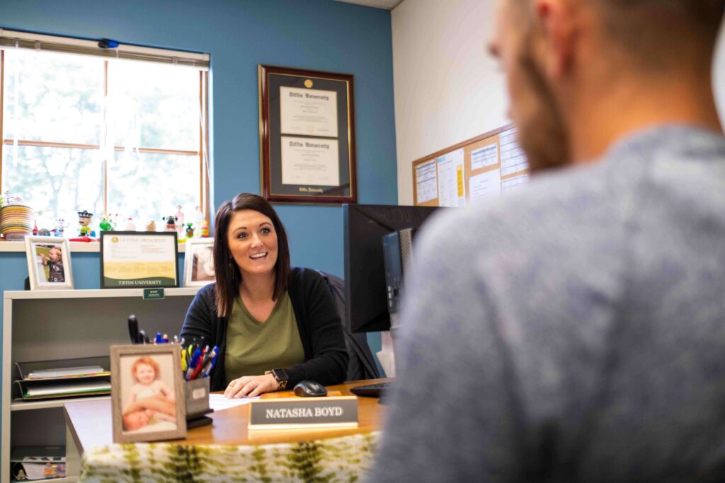 woman at desk with nameplate that says Natasha Boyd