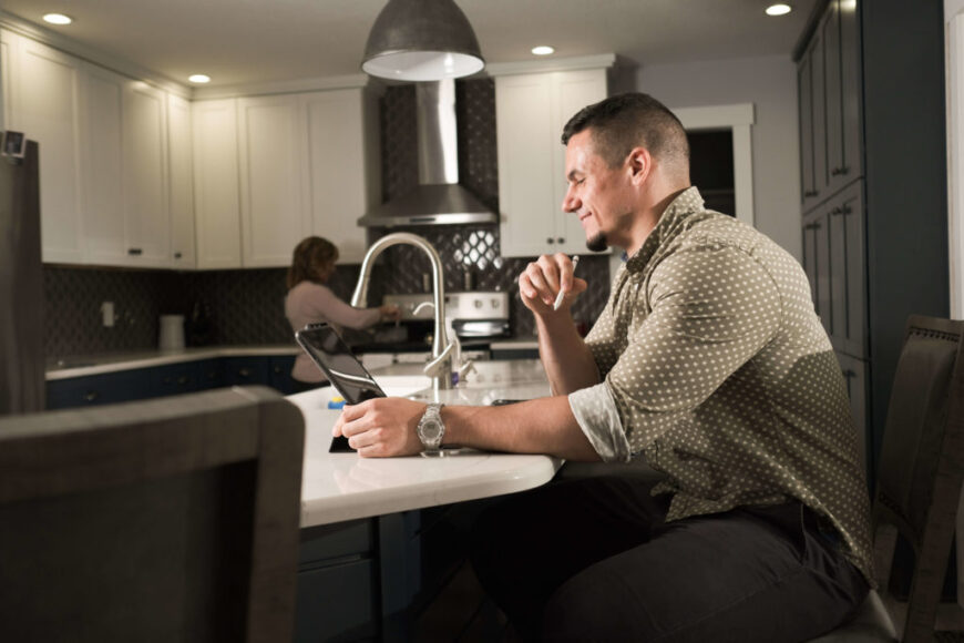 man smiling in front of laptop at kitchen counter