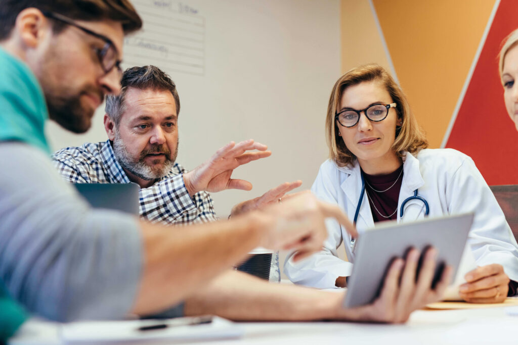 medical professionals at table looking at tablet