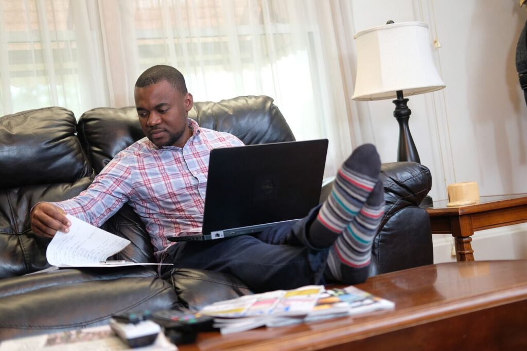 man studying on sofa with socked feet propped on coffee table