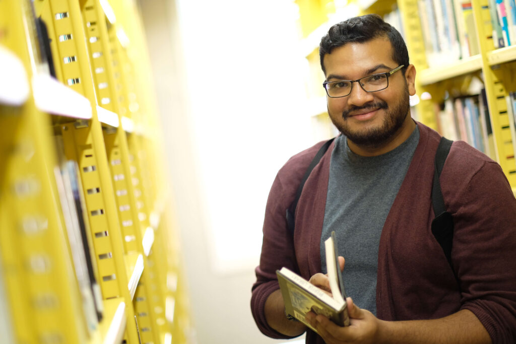 student browsing library shelves to rep bachelor of business administration in marketing