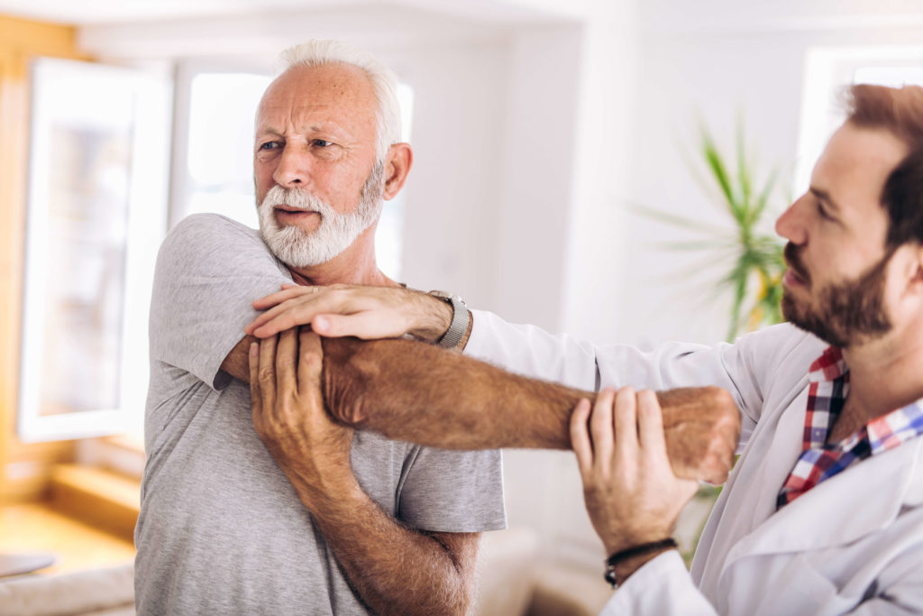 person helping older man stretch arm