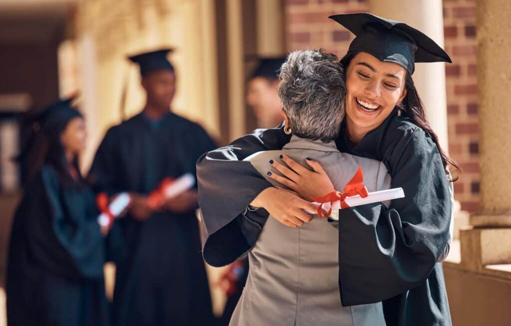 Granddaughter hugging grandma at graduation after earning a college degree