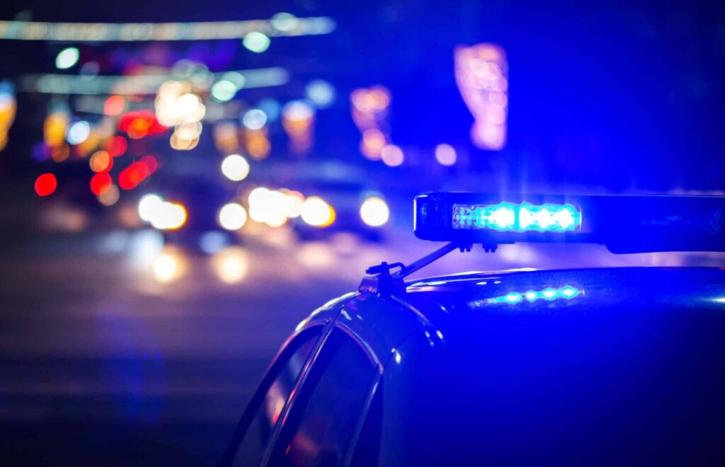 police car with lights on heading to crime scene