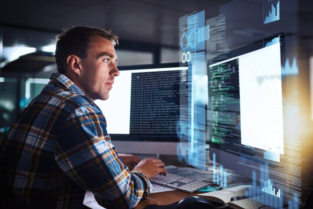 Cybersecurity professional working in an office with several computer screens