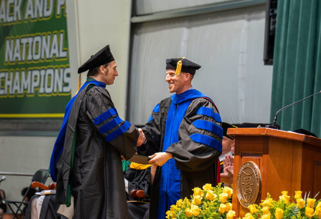 doctoral graduate shaking hands with dean