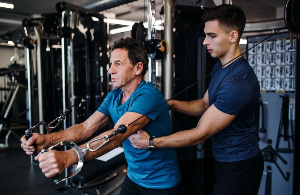 Exercise physiologist helping train a man at the gym