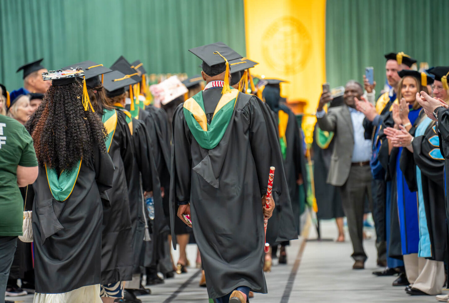 graduates walking as crowd cheers them on