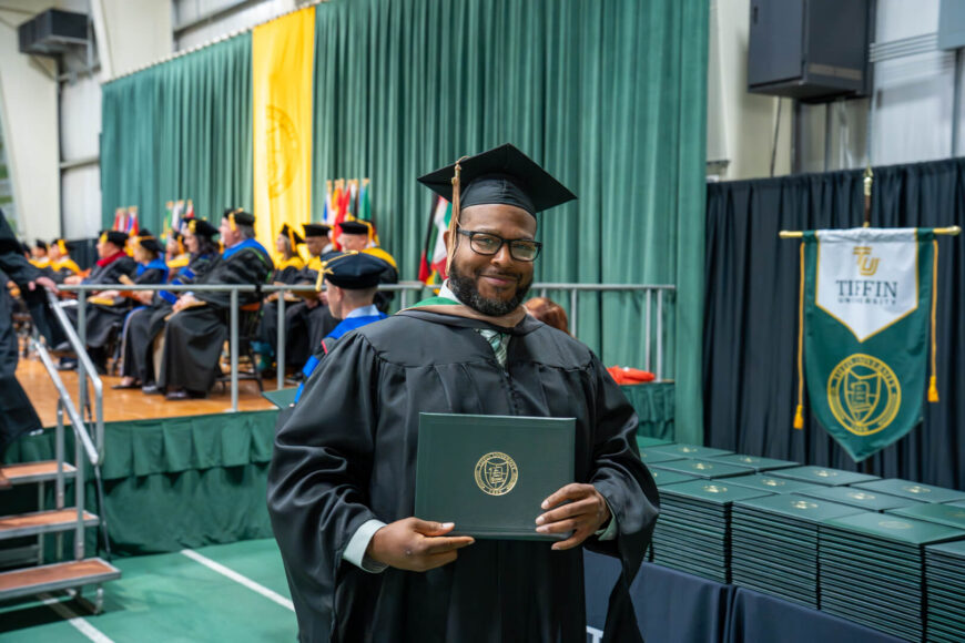 graduate posing with diploma