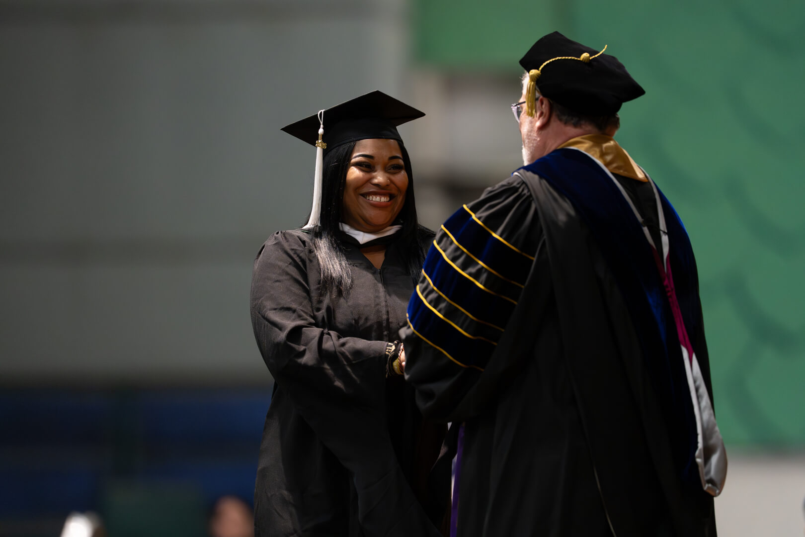 graduate walking across stage and shaking hands