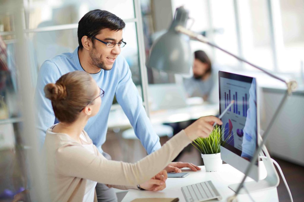 Young employee asking her colleague about data on the screen